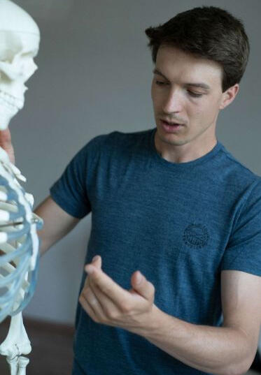 Julian Loic Delaplace beim verständlichen Erklären der Schmerz Symptomatik an einem Skelett für die Patienten.